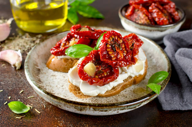 bruschetta with olive oil, sundried tomatoes, cottage cheese and fresh basil - bruschetta cutting board italy olive oil imagens e fotografias de stock