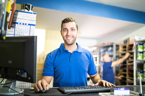 Portrait of a young man using computer working in a paint store