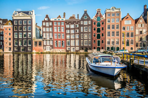 bateau amarré près des bâtiments colorés à amsterdam - magere brug photos et images de collection