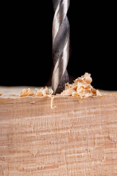 istock Drilling holes in raw wood. Carpentry drill in a carpentry workshop. Dark background. 1167833608