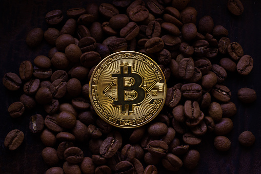 Minsk, Belarus - June 26, 2019: Bitcoin on coffee beans background. Closeup top view