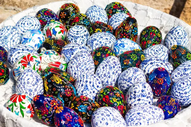 Many eggs in various patterns of a blue shade. Eggs are painted by Easter and stacked in a large plate. The patterns are very beautiful and executed efficiently and accurately.