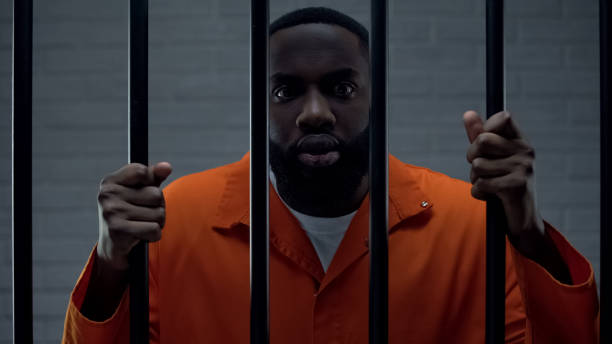 istock Terrified afro-american prisoner holding bars, looking at camera with fear 1167839934