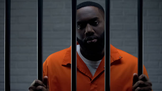 istock Black male prisoner waiting for sentence in prison cell, looking sadly to camera 1167839955