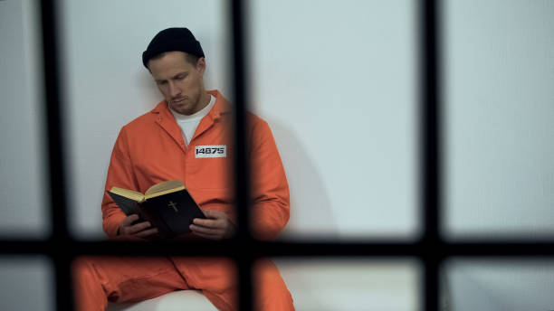 Caucasian prisoner reading bible in cell, convicted sinner turning to religion Caucasian prisoner reading bible in cell, convicted sinner turning to religion killercell stock pictures, royalty-free photos & images