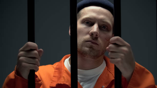 istock Crying prisoner holding bars and looking to camera, feeling guilty and desperate 1167840302