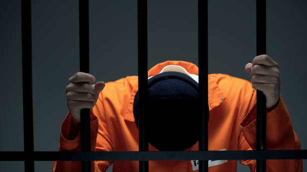 istock Male prisoner holding bars and leaning head, feeling depressed and guilty 1167840338