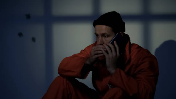 Imprisoned male making phone call, prison rules violation, gadget prohibition Imprisoned male making phone call, prison rules violation, gadget prohibition killercell stock pictures, royalty-free photos & images