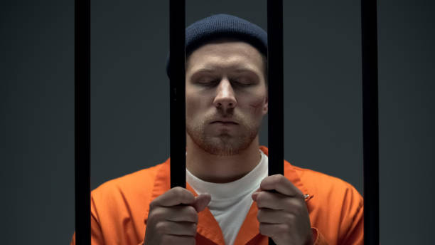 istock Imprisoned Caucasian man holding cell bars with eyes closed, depression problem 1167840343