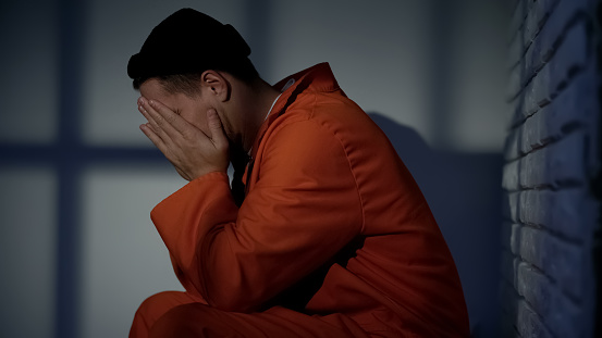 Anxious prisoner in cell feeling desperate, regretting about crime and mistakes