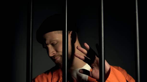 istock Prisoner closing eyes with hand, warden flashing with torch, security checkup 1167840400