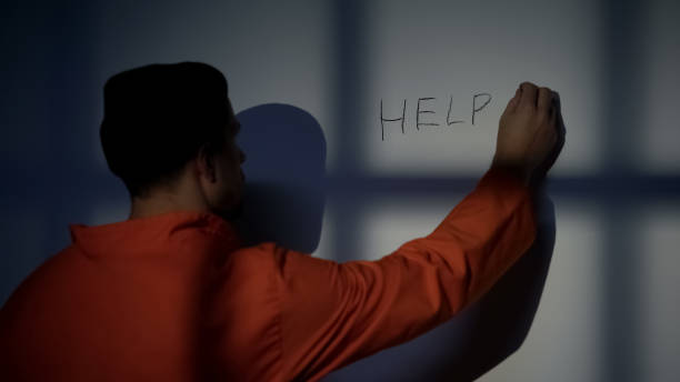 istock Prisoner writing Help word on cell wall calling for help, ill treatment, abuse 1167840459