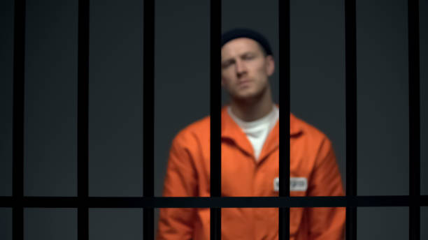 istock Blurred dangerous prisoner standing behind prison bars, justice, law and order 1167840463