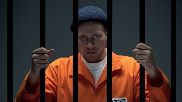 istock Angry Caucasian prisoner with scared face looking through cell bars, danger 1167840470