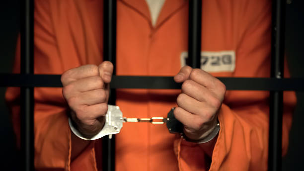 istock Prisoner showing hands in handcuffs, dangerous criminal standing behind bars 1167840473