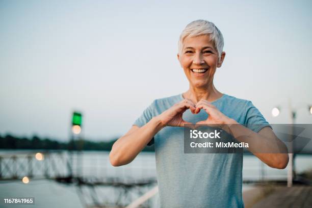Active Senior Woman Making A Heart With Her Hands Stock Photo - Download Image Now - Healthy Lifestyle, Heart Shape, Senior Adult