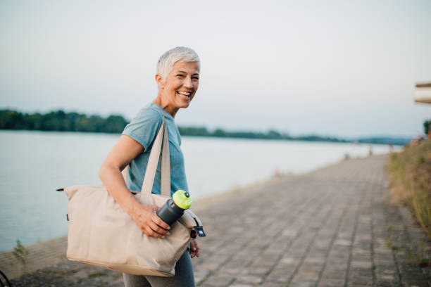 Happy senior woman finishing her training Happy senior woman finishing her jogging on the riverbank. DisruptAgingCollection stock pictures, royalty-free photos & images