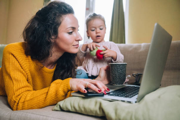 istock Mother and daughter using laptop on sofa 1167845906