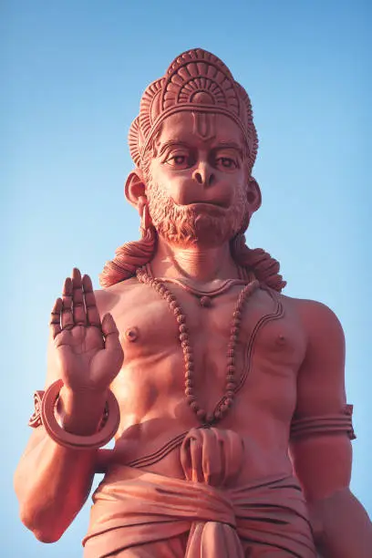 The bottom view on a huge statue of red Hanuman with the raised hand in blessing gesture.