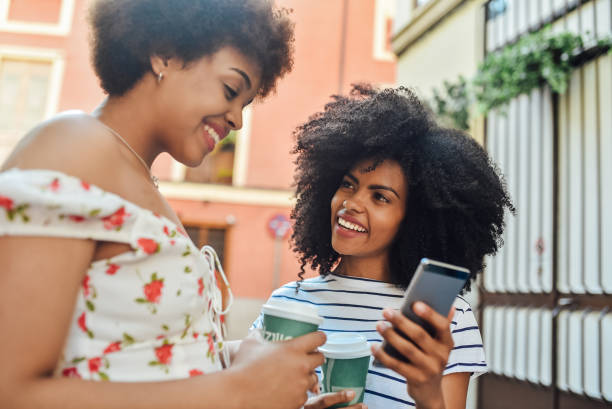 istock Two girlfriends drinking coffee and having fun on social media outdoors 1167848083