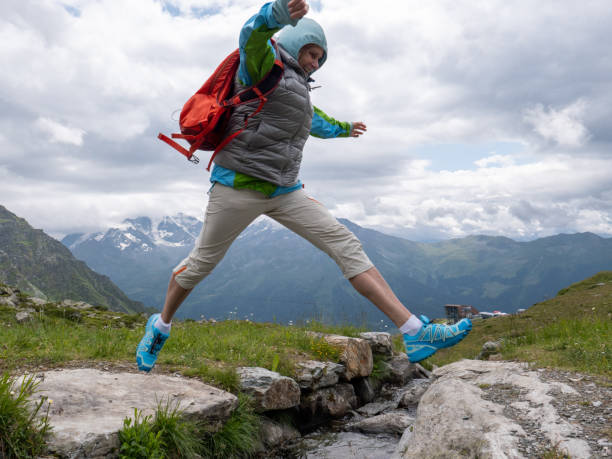 istock A woman on a hike leaping over a mountain stream 1167848228