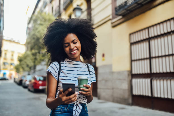 istock Beautiful girl texting and drinking coffee on the way 1167849015