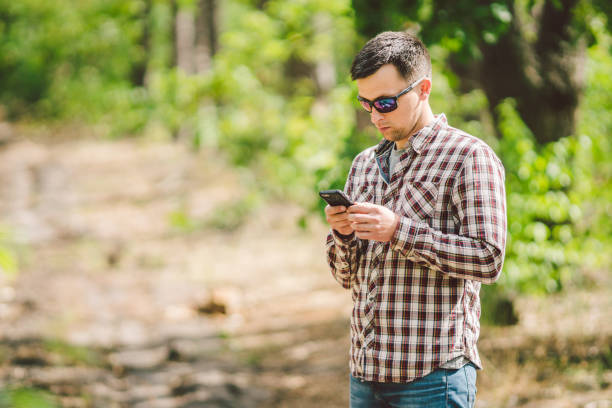 istock Hipster young man with backpack using smart phone on beautiful nature.Travel concept. Outdoor travel. Travel and explore. Backpacker male Going in forest Gps Route. Portrait hiker using mobile phone 1167856612