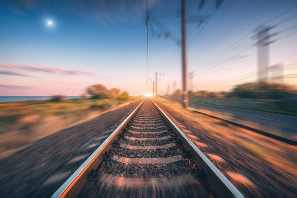 istock Railroad and beautiful blue sky with full moon at sunset with motion blur effect in summer. Industrial landscape with railway station and blurred background.  Railway platform in speed motion. Concept 1167856652
