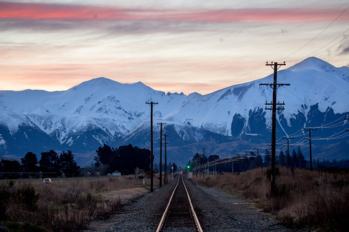 The sun goes down over the snowy Torlesse Range mountains in winter time, creating pastel colours against the evening sky in Canterbury, New Zealand