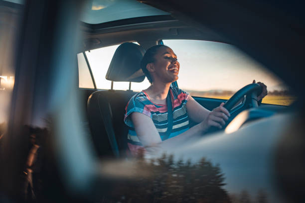 mulher nova que conduz o carro em um dia ensolarado - adventure african ethnicity rural scene day - fotografias e filmes do acervo