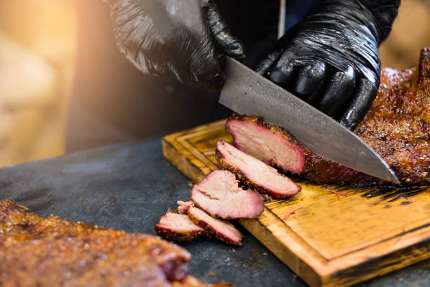 culinary master class chef smoked beef brisket Culinary master class. Cropped shot of chef in black cooking gloves using knife to slice smoked beef brisket. brisket photos stock pictures, royalty-free photos & images
