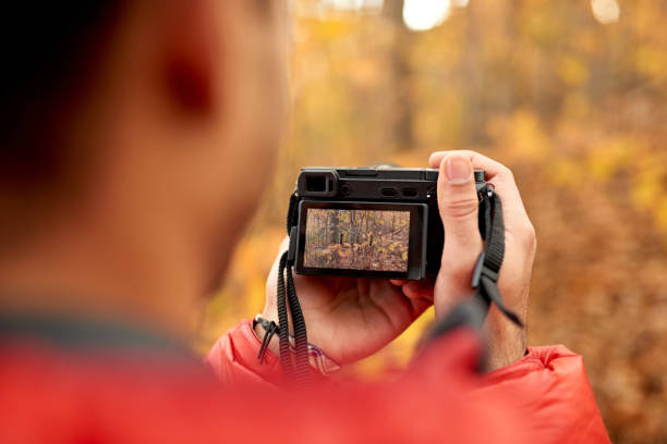 istock Attractive indian man taking pictures with a mirrorless camera through the forest in the fall in Canada 1167864221