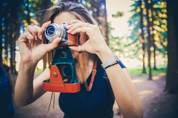 istock Woman taking photos with retro camera in forest. 1167870962