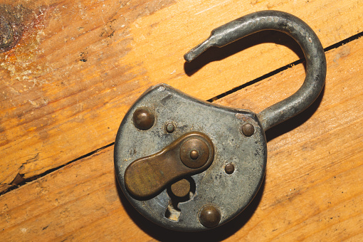 Old rusty lock on a wooden table. Vintage padlock on wood background