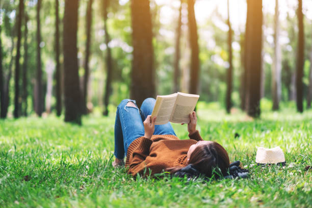 istock woman lying and reading a book in the park 1167877781