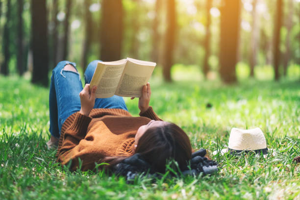istock woman lying and reading a book in the park 1167877783