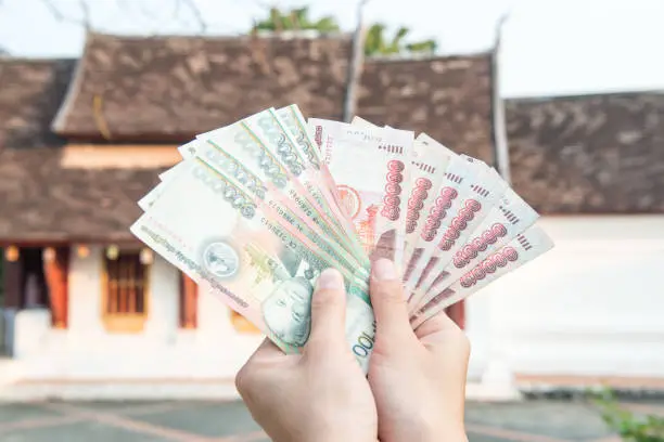 Photo of Cropped shot view of someone holding banknotes of Laos kip money the national currency of Laos.