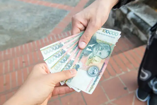 Photo of Cropped shot view of someone giving or payment banknotes of Laos kip money to other person.