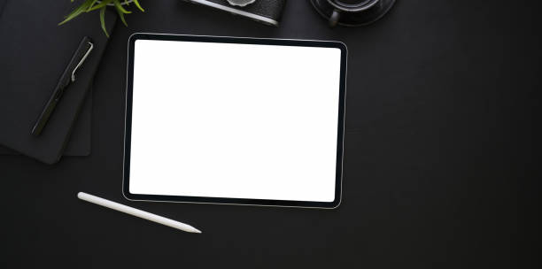 istock Blank screen tablet and office supplies in dark stylish workplace 1167882129