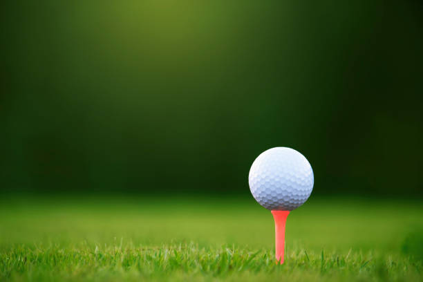 мяч для гольфа на тройнике в красивом поле для гольфа - golf golf flag sunset flag стоковые фото и изображения