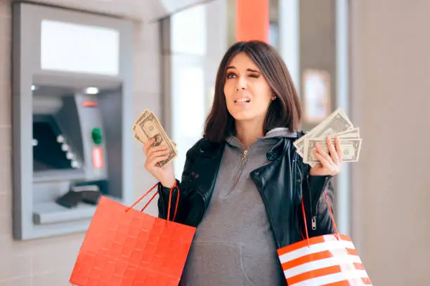 Photo of Big Spender Holding Money in front of the ATM