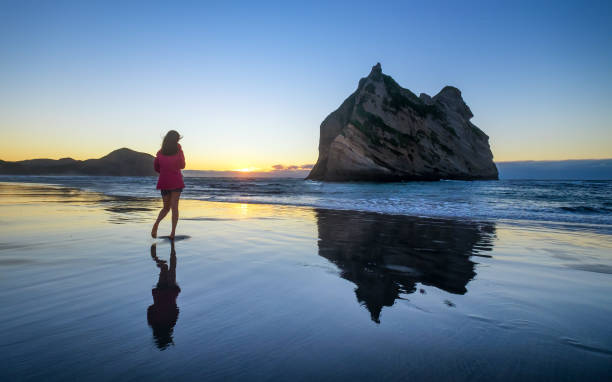 istock Girl alone at beach with reflective sand. 1167887788