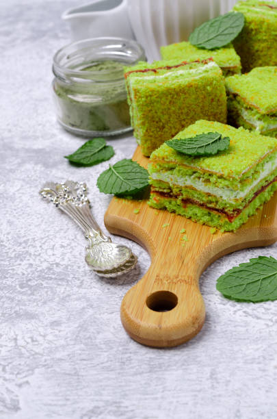 Traditional green sponge cake with cream and jam on slate background. Selective focus.
