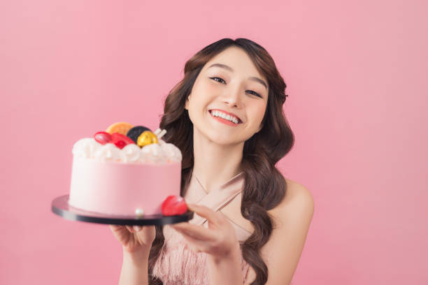 istock Generous woman holding birthday cake front pink background 1167890019