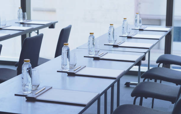istock Plastic water bottles, Drinking glasses with pencil and white papers setup on the table prepared for seminar or business meeting in the hotel conference room 1167893977