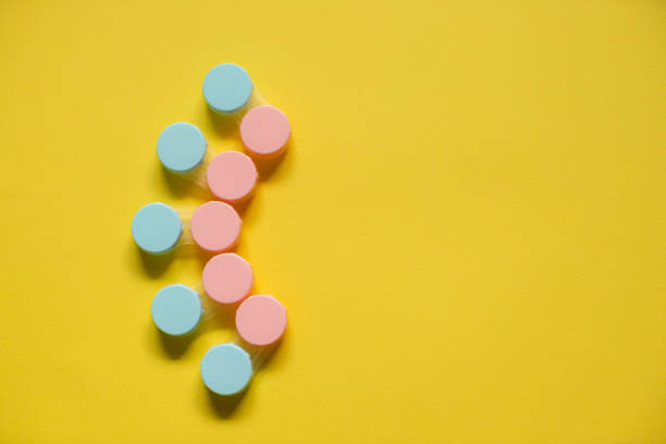 istock Pink and blue contact lens cases on yellow background with empty copy space 1167896826