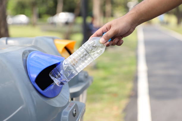 istock close up man hand throw empty plastic bottle into the garbage in park on sunny day with green tree blurred background 1167897835