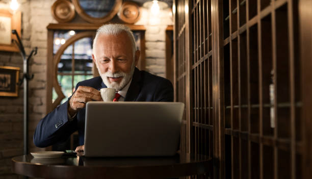istock Elderly businessman manager working on his laptop in a cafeteria 1167906056