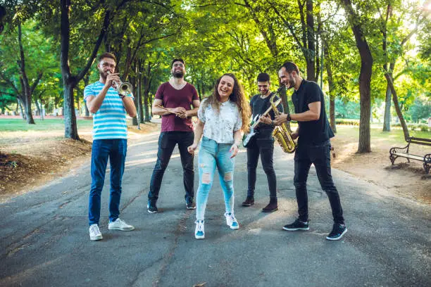 Young band in public park posing with their instruments.