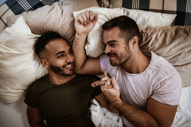 istock Multi ethnic LGBT couple waking up in bed and smiling 1167907123
